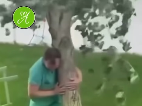 Un padre sostiene un árbol que había plantado su hija antes de morir